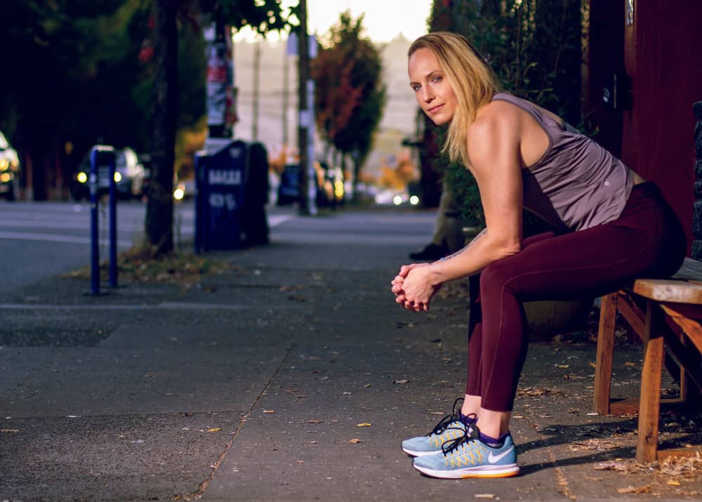 Ashley Kondziela sits on a bench in workout gear in Portland, OR